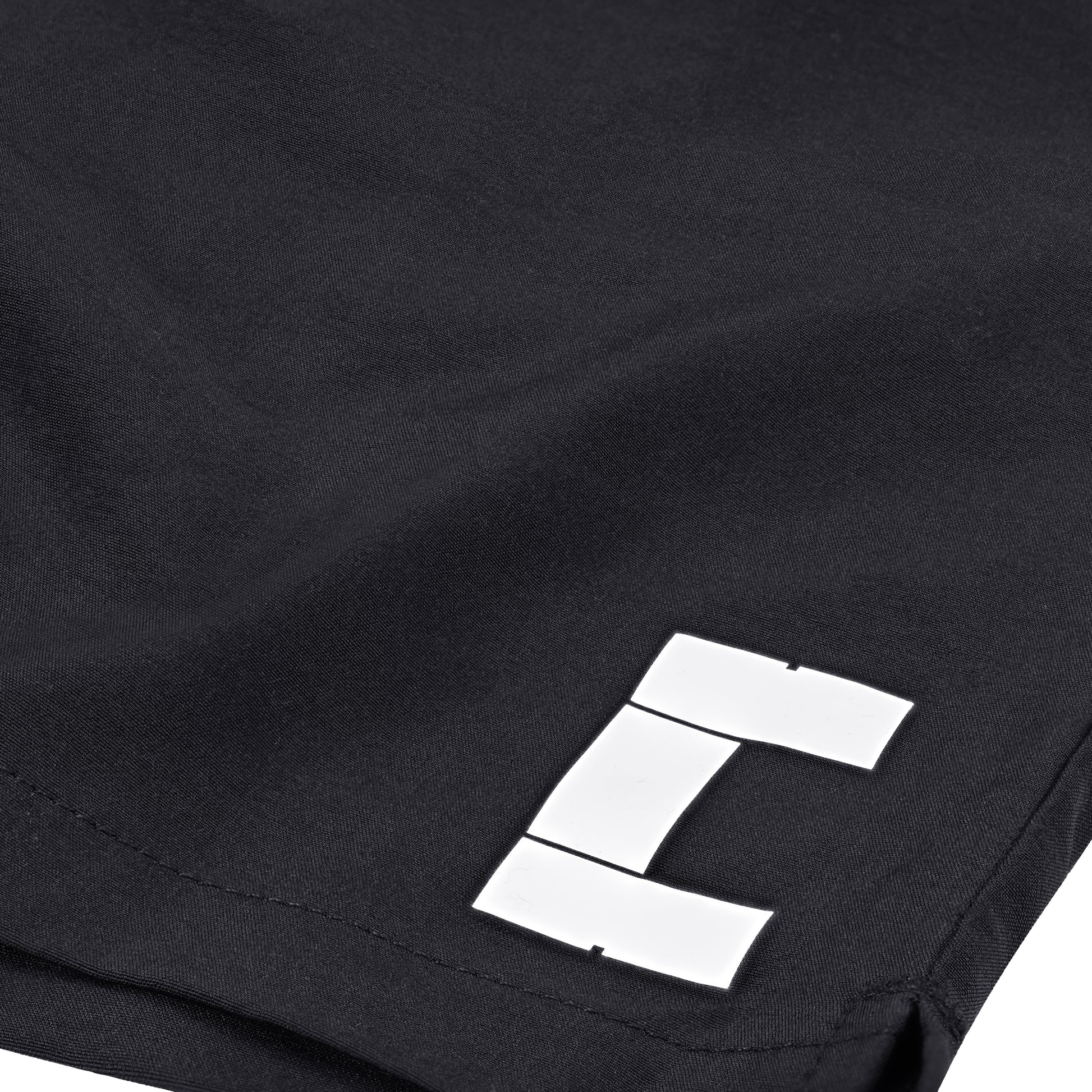White logo detail of black Court10 Performance Shorts on a white background